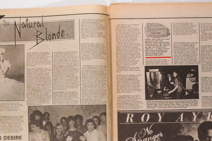 An open vintage magazine or newspaper spread laid flat on a white surface, showing two printed pages with black-and-white photos, columns of text, and several colored headlines including 'Natural Blonde,' 'Burning Desire,' 'Pet Project,' and 'Roy Ayers Mr. Stranger To Love.