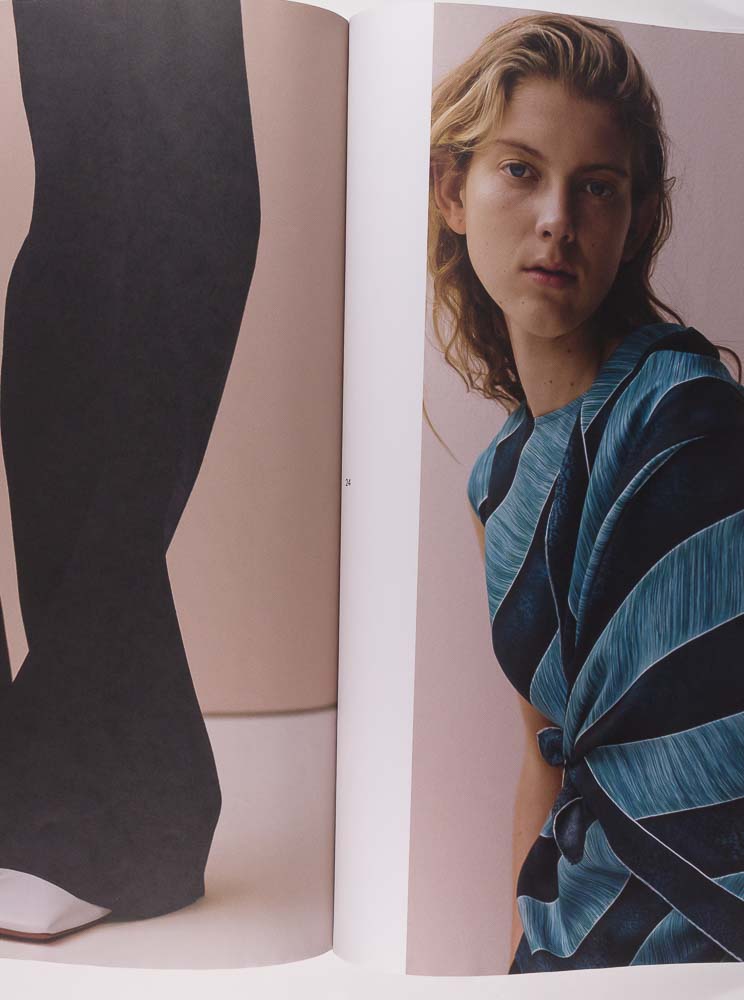 Open magazine showing a page with a close-up of black pants and another with a person wearing a blue and black striped top.